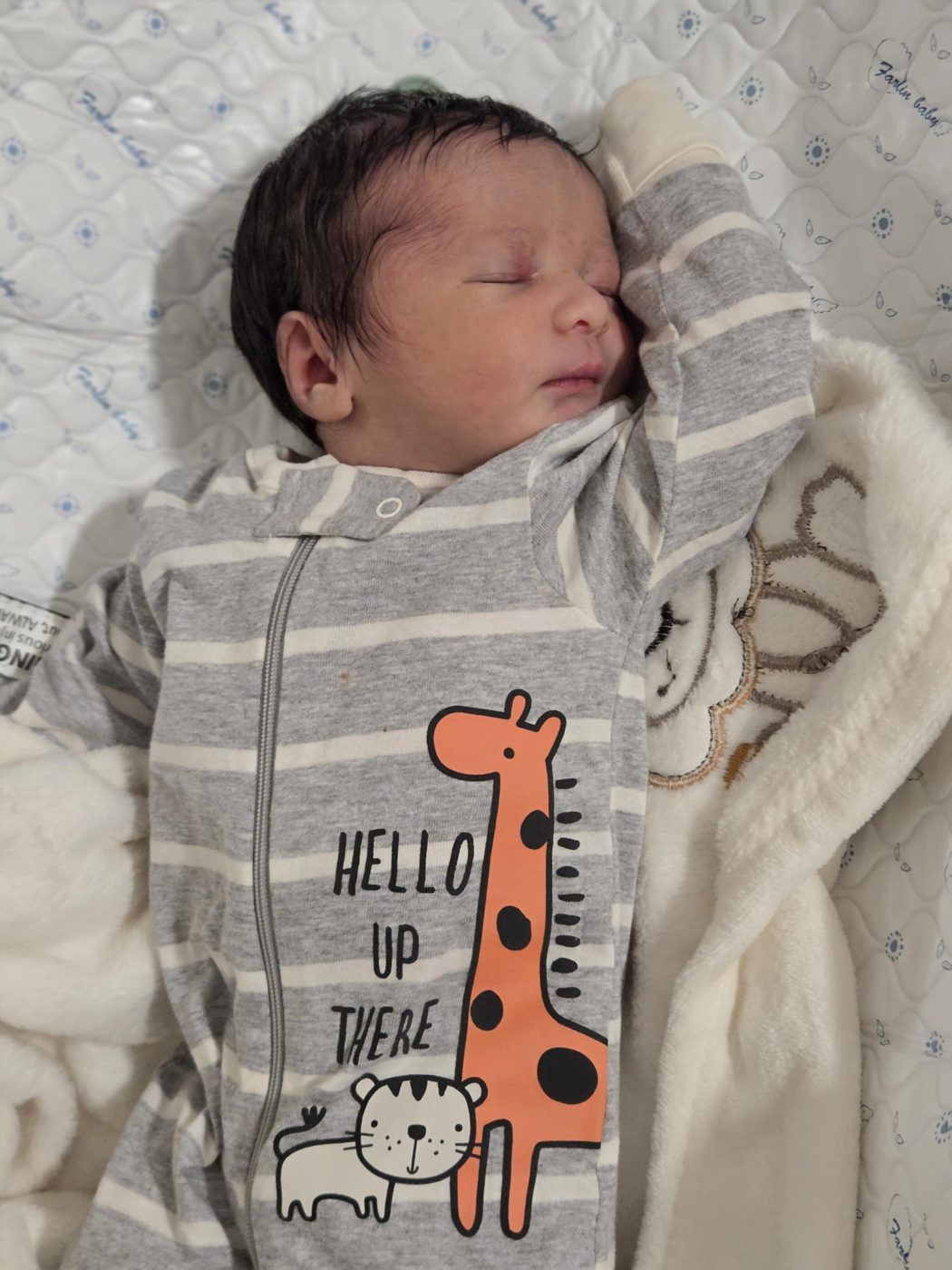 Faris sleeping in a grey striped sleeper that says Hello Up There